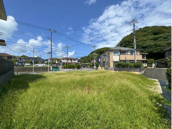 北側の向かいは駐車場。遠巻きに山があり緑と青空のコントラストが素敵です